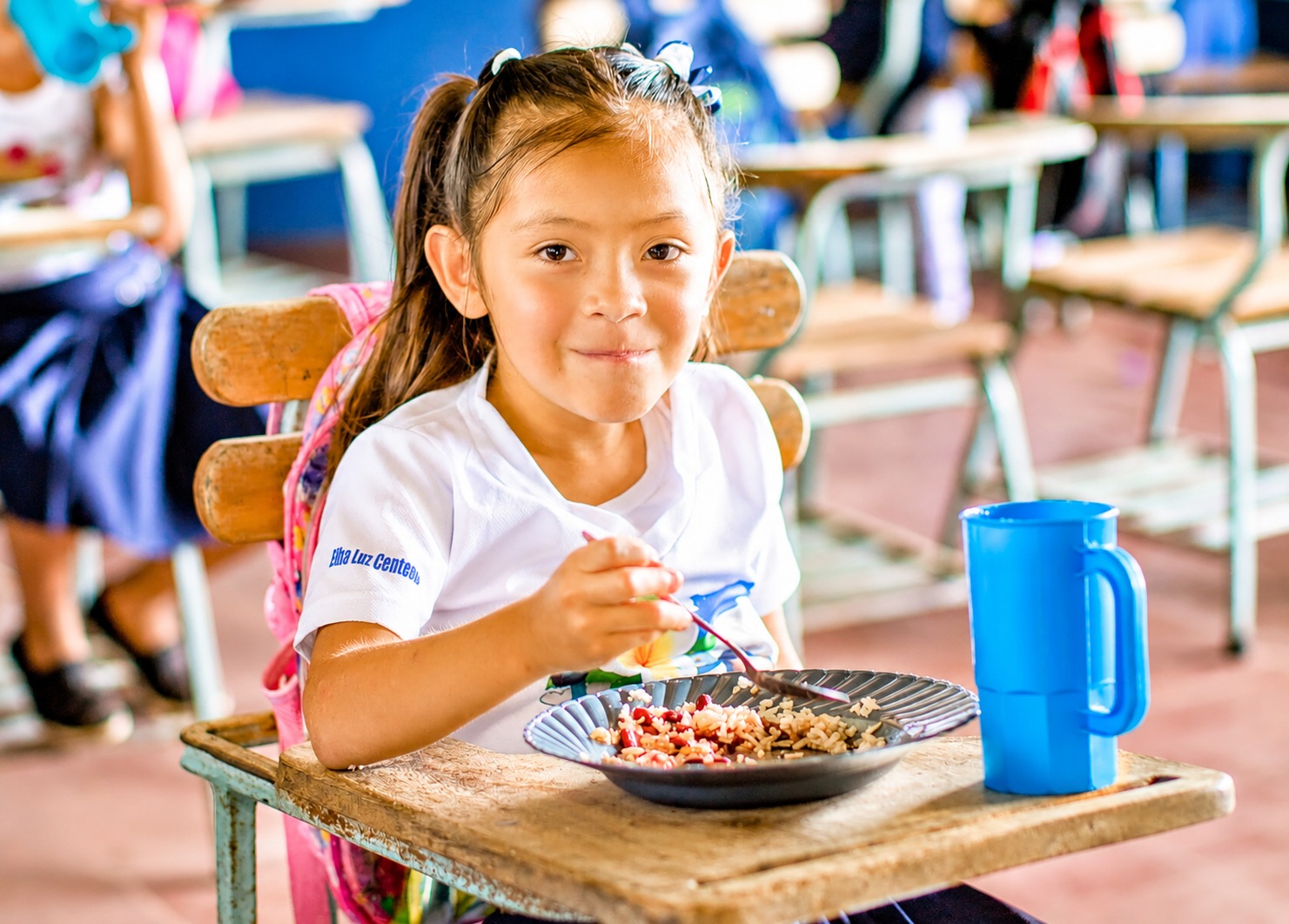 A schoolchild eating a meal at a classroom desk